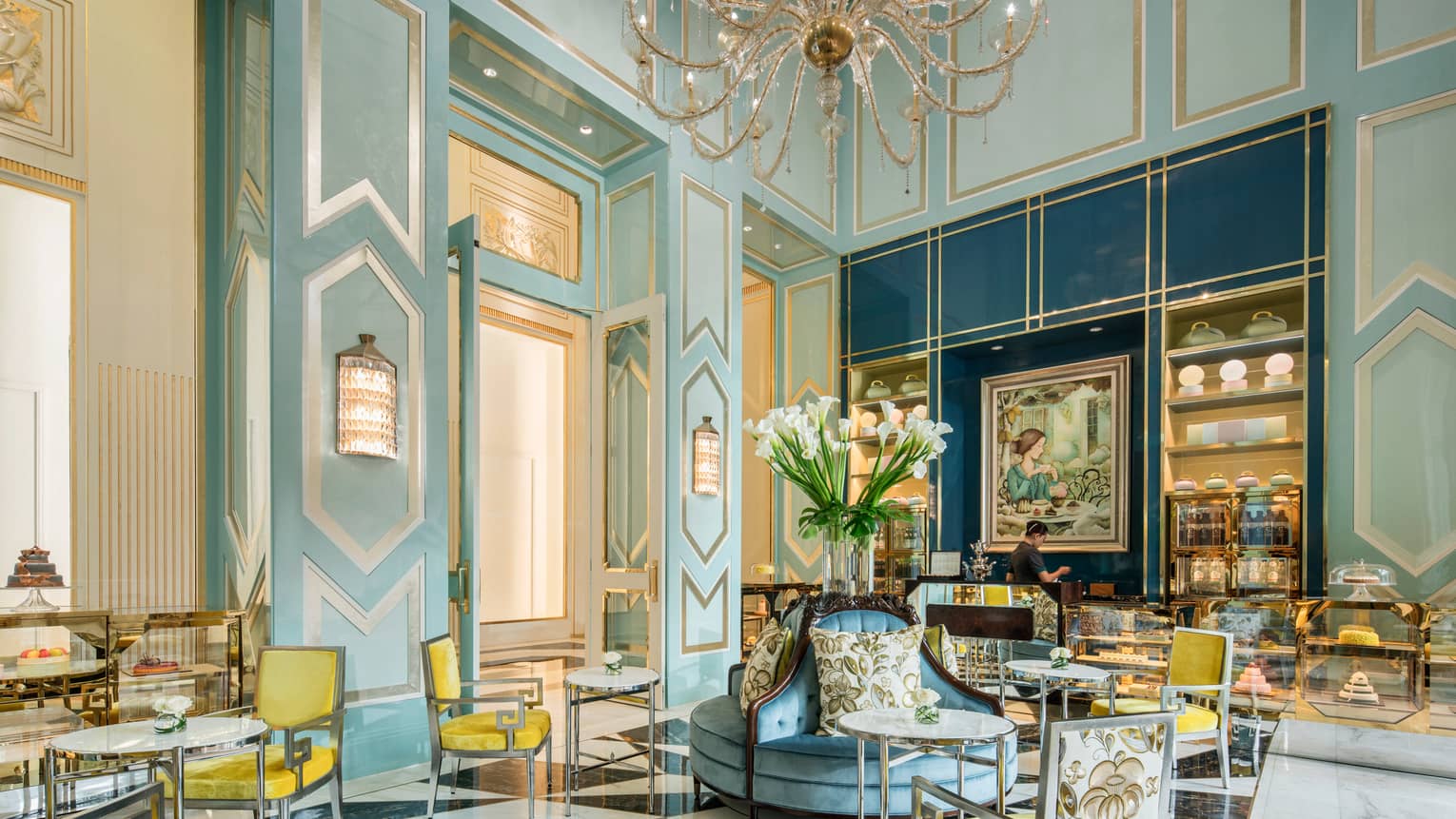 Bright La Patisserie cafe with elegant blue decor, yellow chair, high ceilings, crystal chandelier