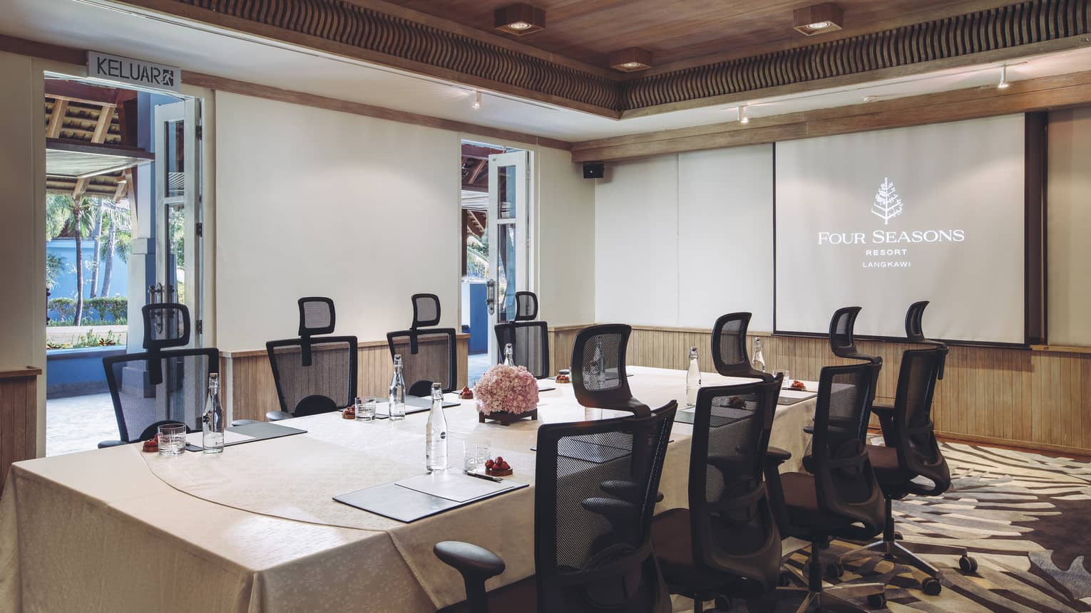 Meeting room with large rectangular table, 8 chairs and screen