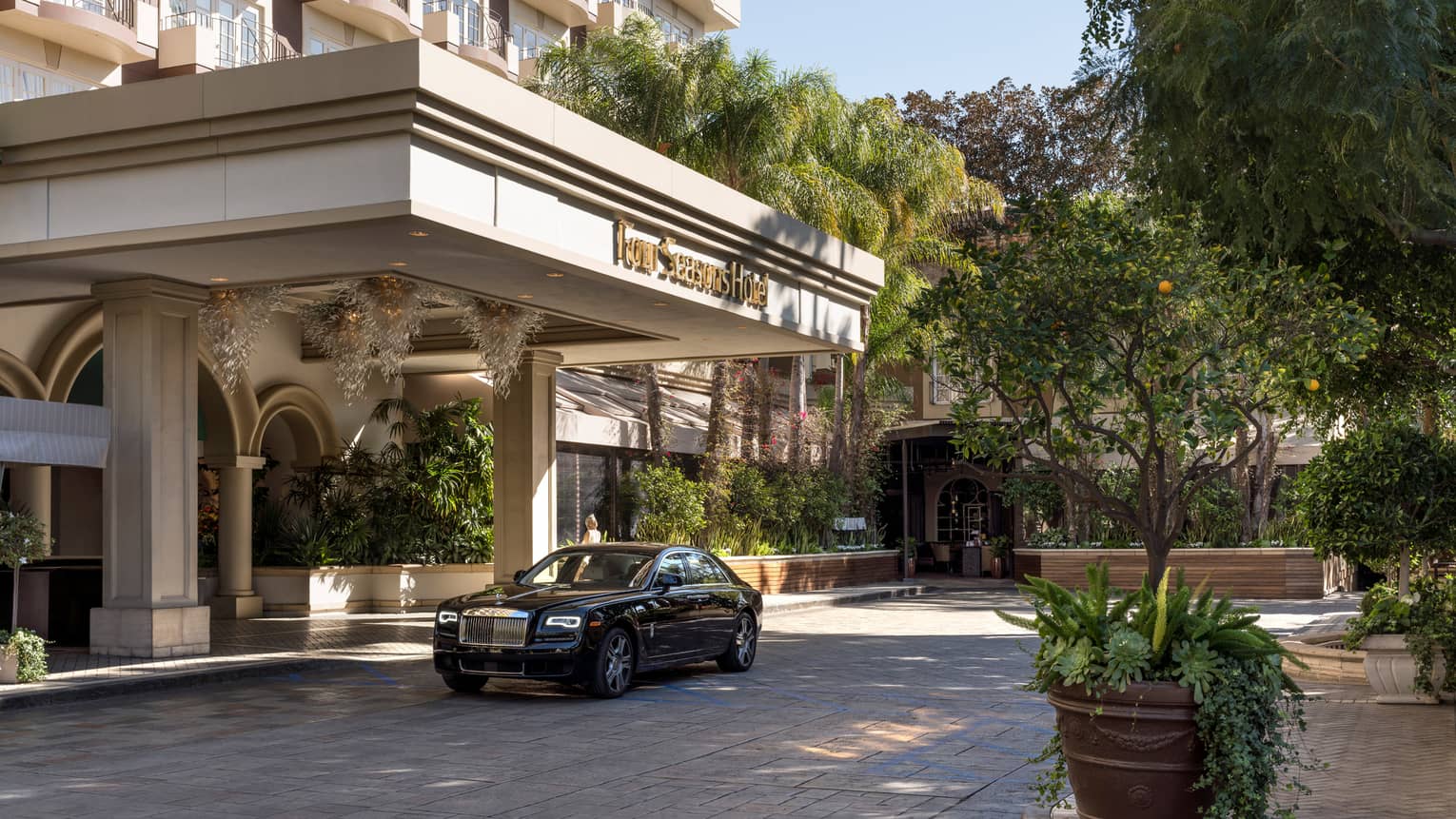The exterior of a hotel with a car parked outside of its entrance on a driveway.