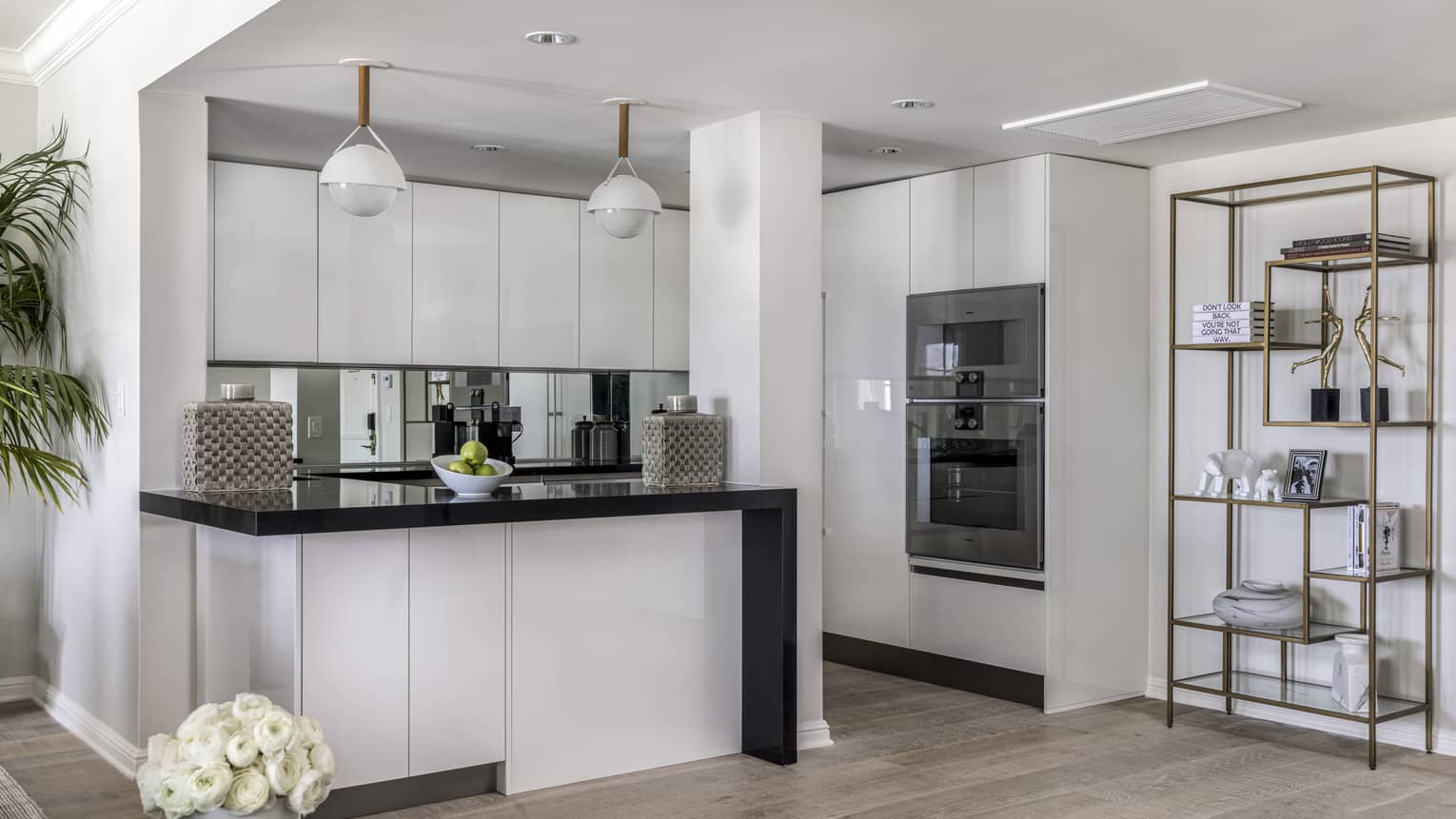Kitchen with white cupboards, black counter, two hanging lights