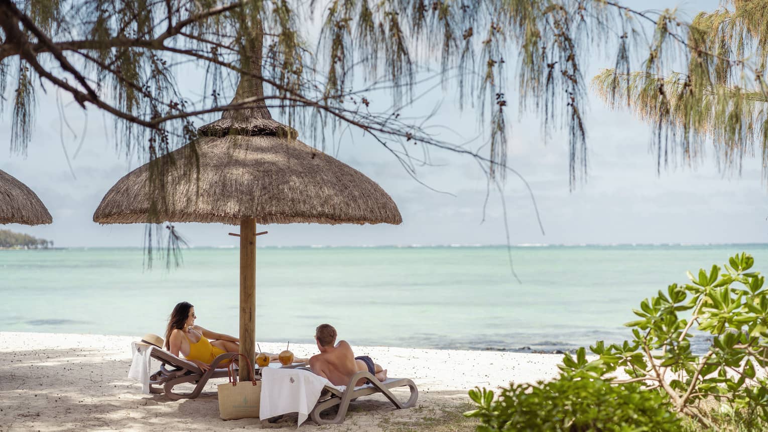 Couple relaxes on beachside chaise lounges