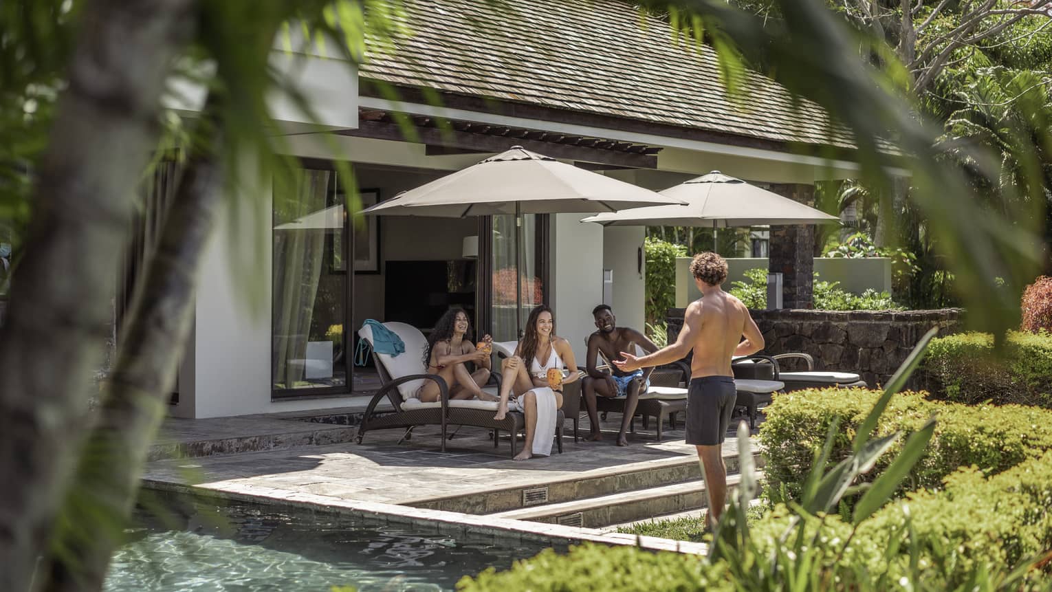 A group of four friends relax poolside at their Four-Bedroom Deluxe Residence