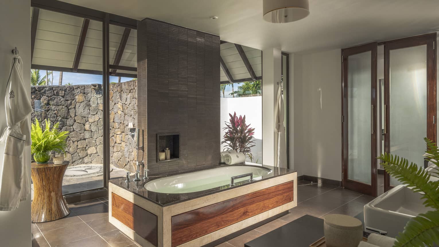 Large bathroom with wooden-framed tub, walk-out stone terrace