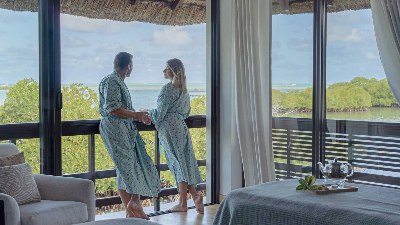 Couple in matching bathrobes stand on the balcony of their Spa treatment room