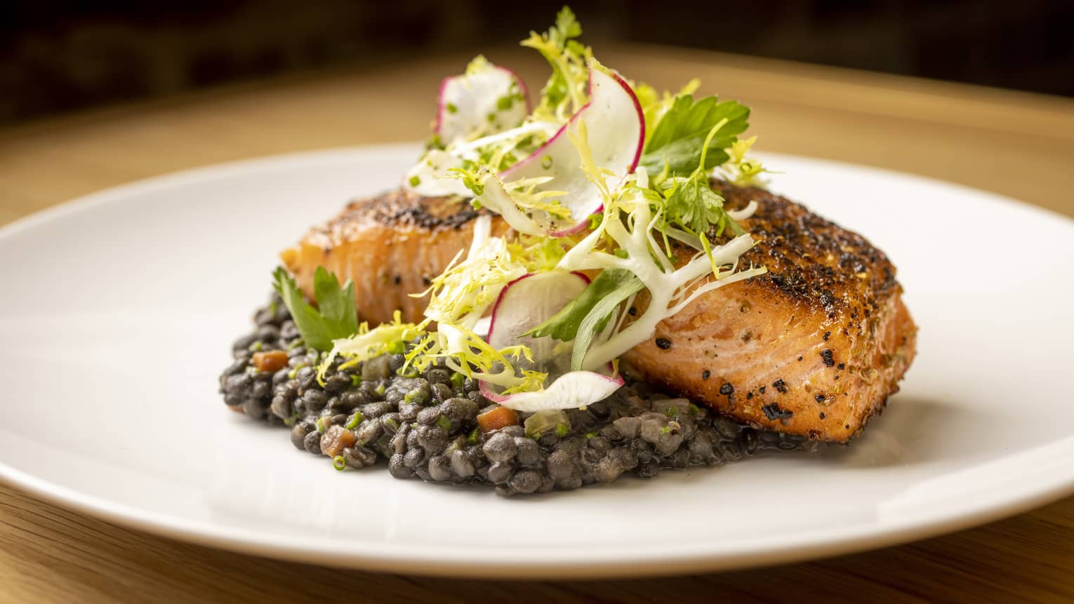 Pan-seared salmon on a bed of Beluga lentils, topped with fris?e and radish salad