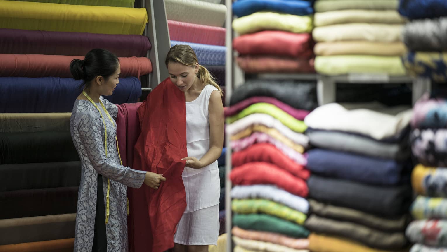 Two women standing in a room of fabric.