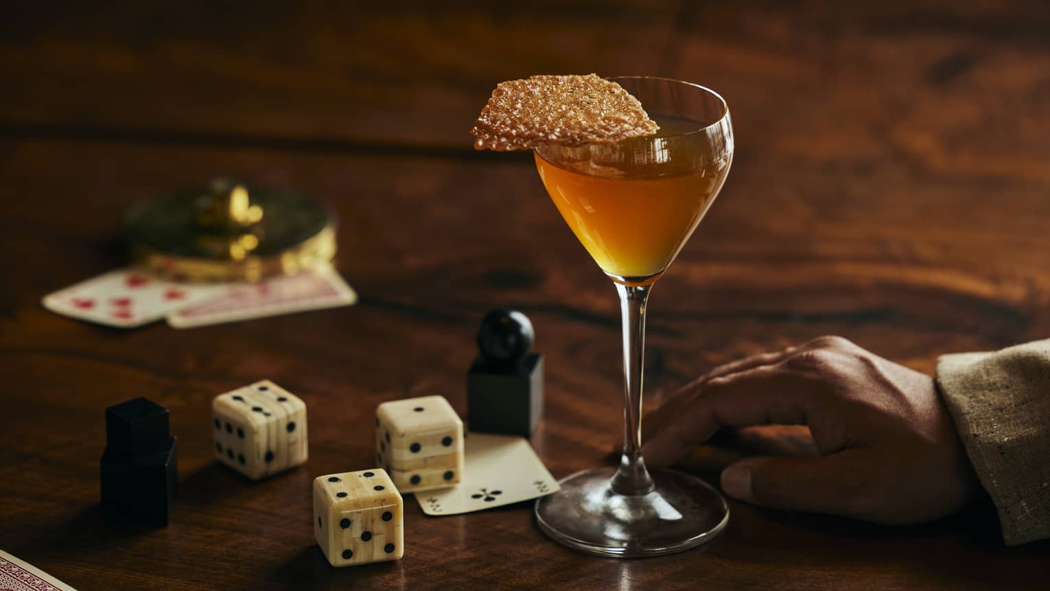 Cognac cocktail on a bar table next to cards and dice