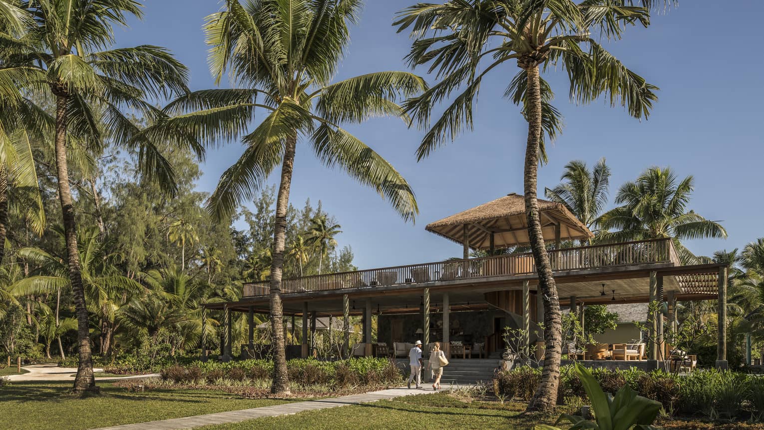 Couple walk up to Welcome Lounge with open-air rooftop, surrounded by palm trees