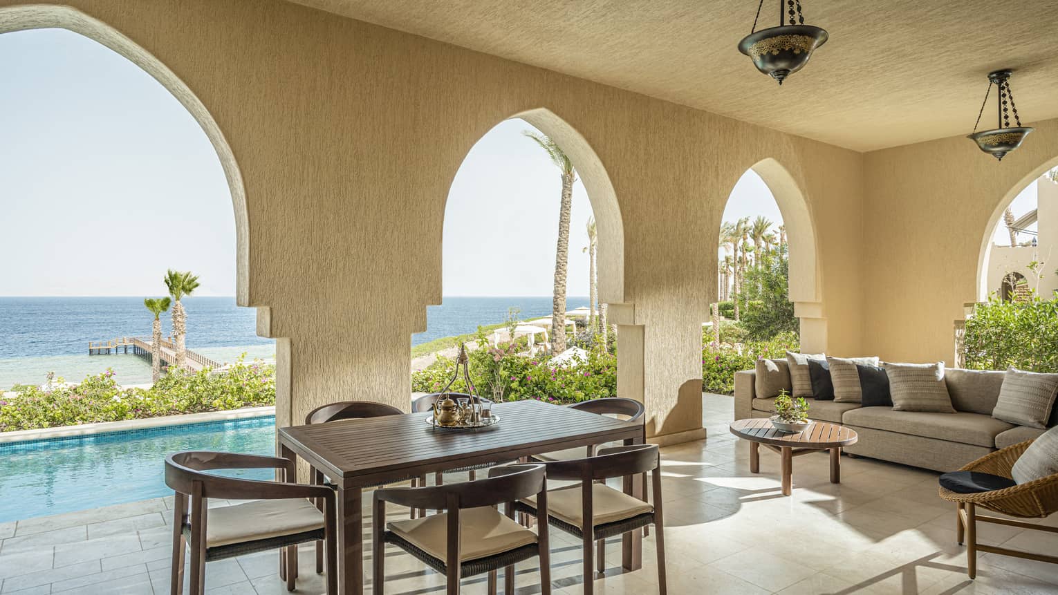Imperial Suite terrace with cafe table, cream sectional sofa, archway leading to pool, views of the Red Sea
