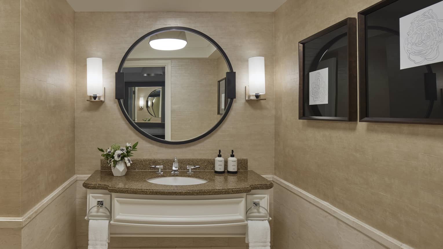 A bathroom with round mirror and sink.