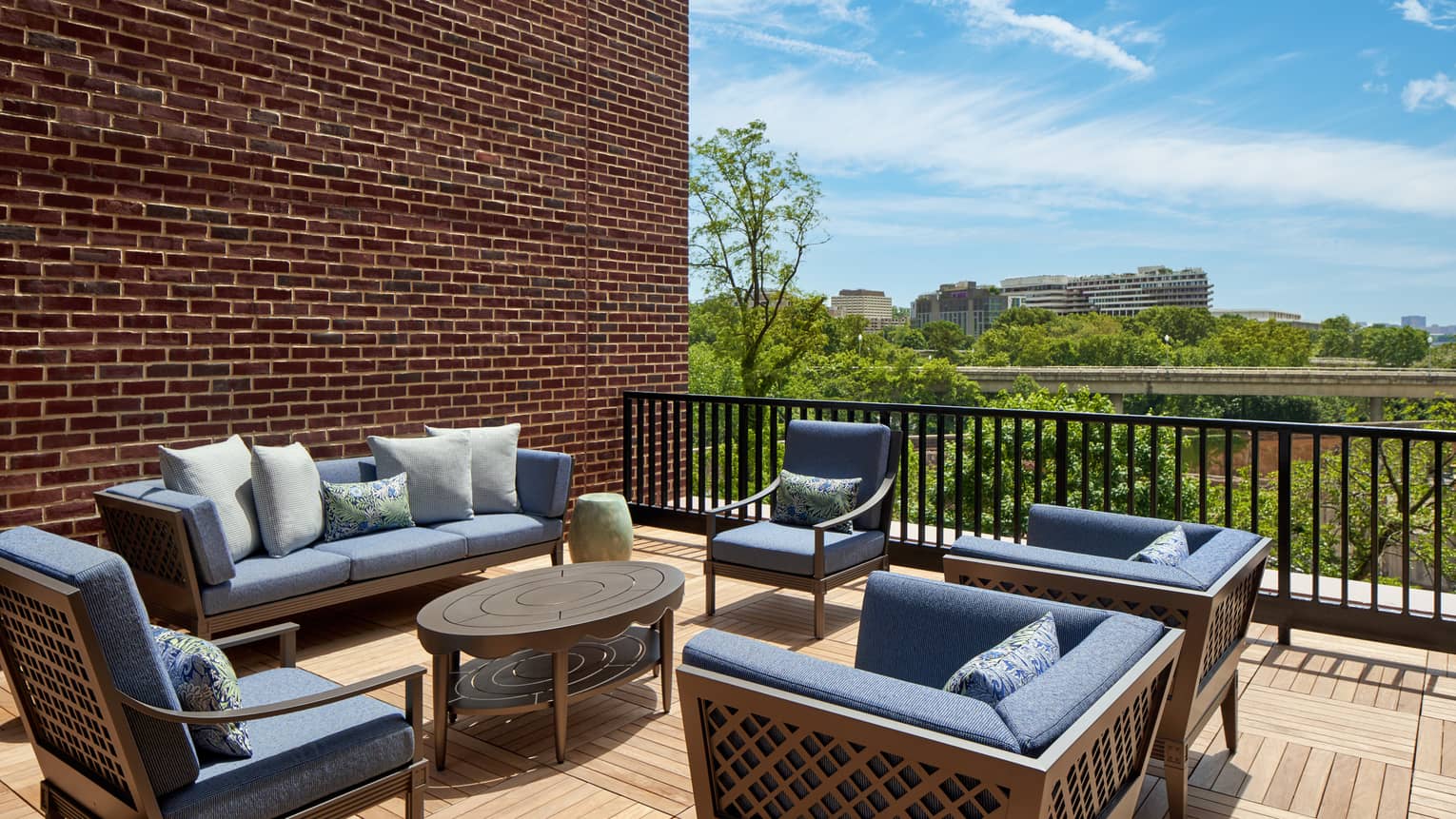 Large outdoor suite terrace with wooden floors and expansive lounge seating featuring dark blue cushions, at Four Seasons Hotel Washington, DC