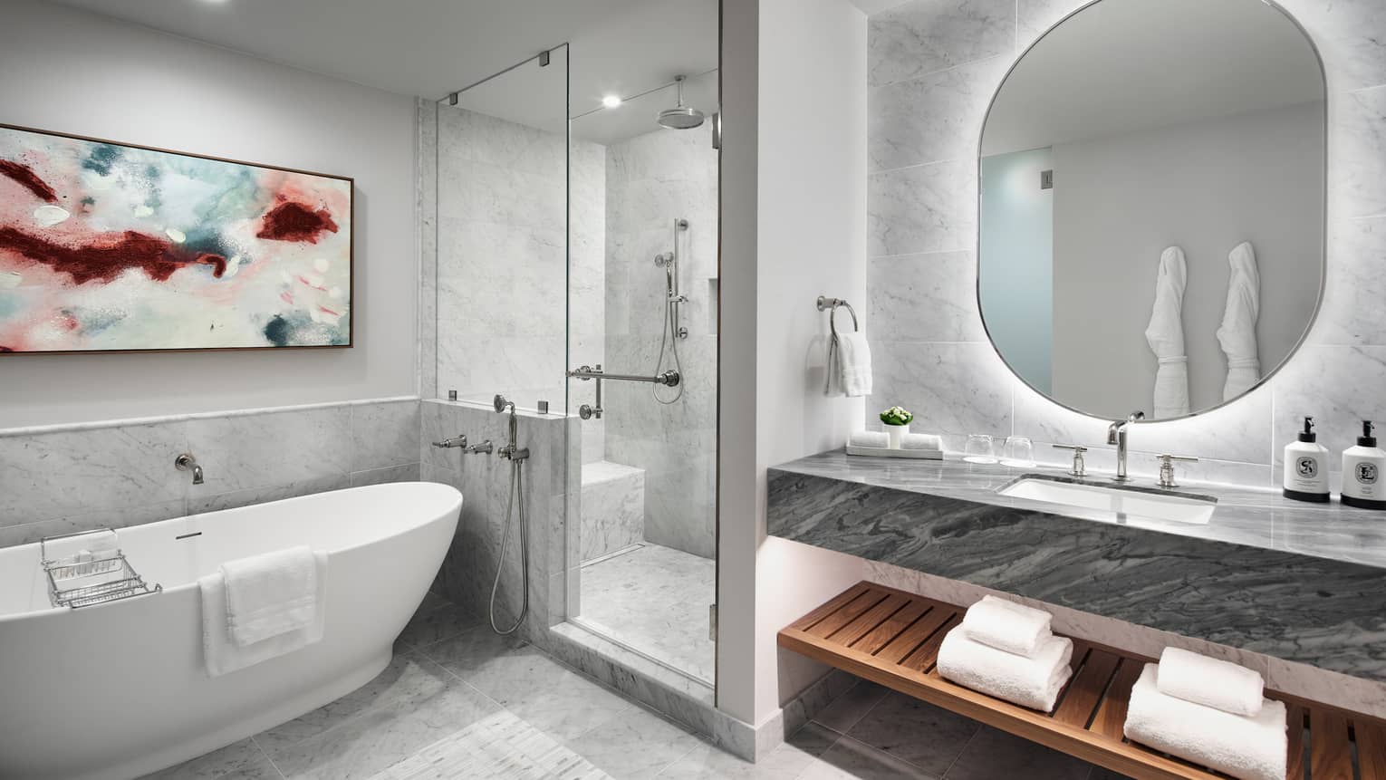 Luxury hotel suite bathroom with marble walls and floors, walk-in shower and deep-soaking tub