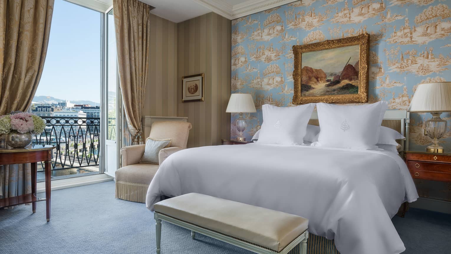 Suite Léman with antique-style blue wallpaper, painting with gold frame above bed next to open French doors with lake view