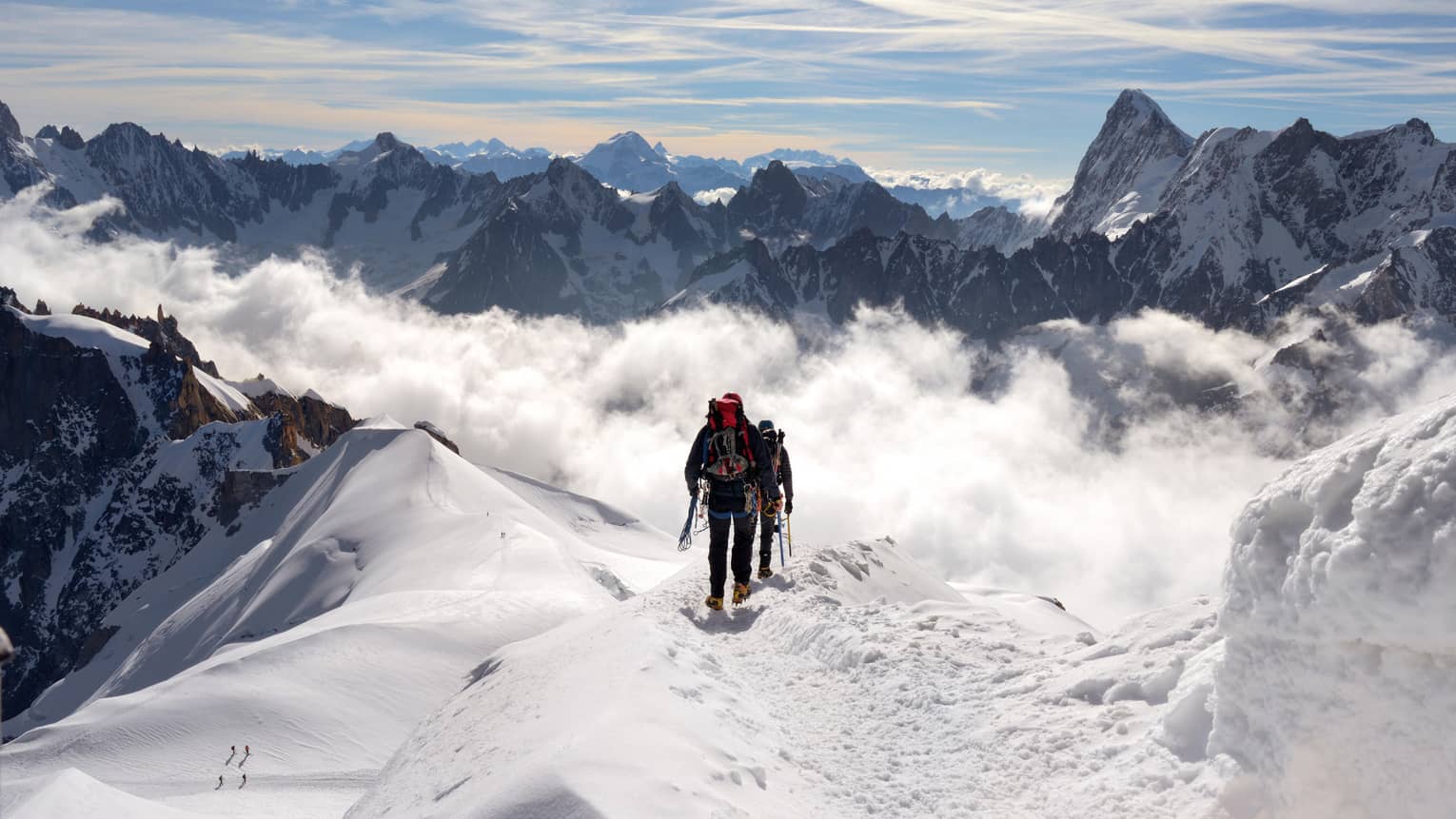 Two people hiking at top of icy mountain in French Alps
