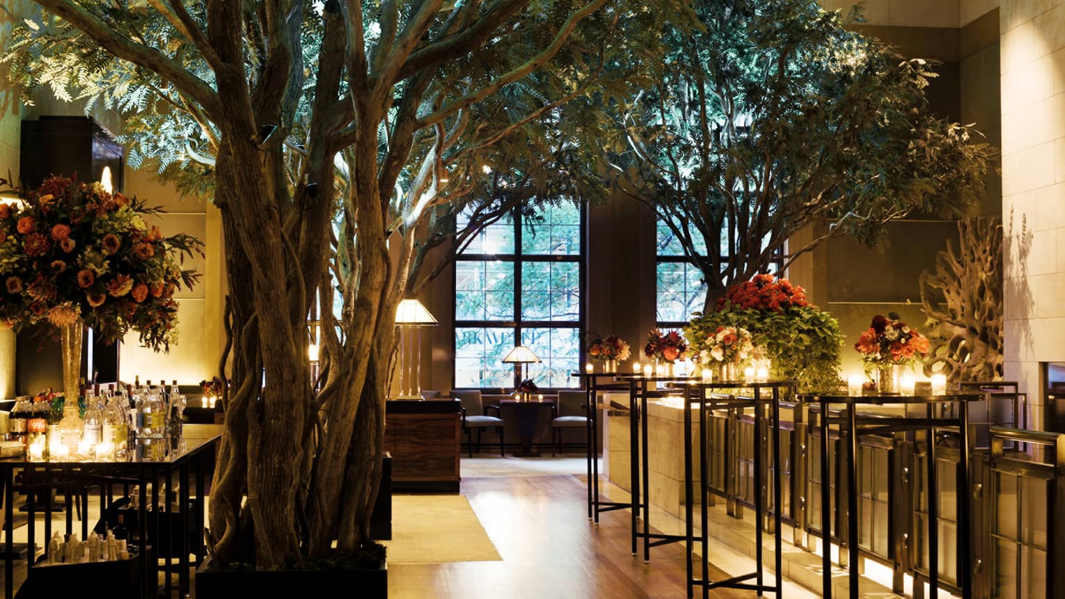 Dark lounge with candles on cocktail table, potted indoor trees