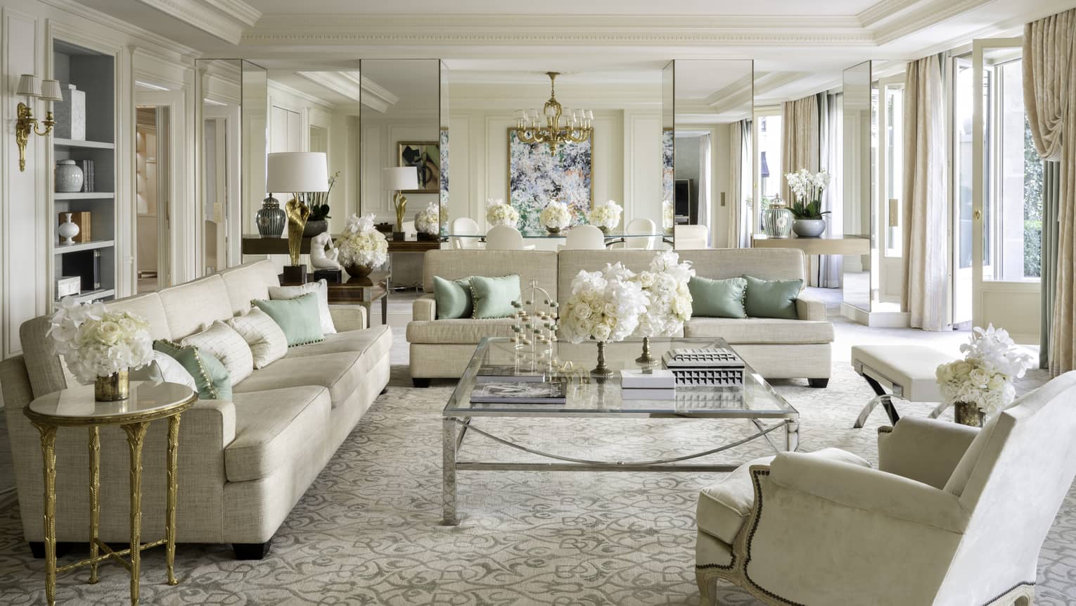 Royal suite with two couches, an armchair, coffee table, cream & teal accents, natural light 