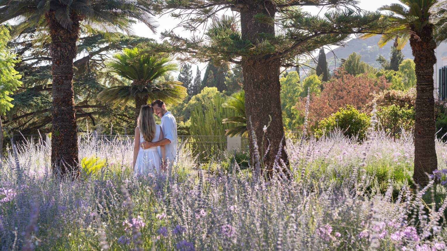Couple walks through field of lavender flowers flanked by palm trees