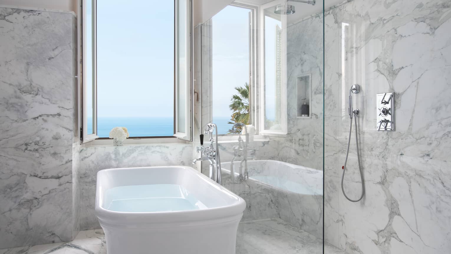 Bathroom with marble walls and floor, free-standing white tub facing sea-view window