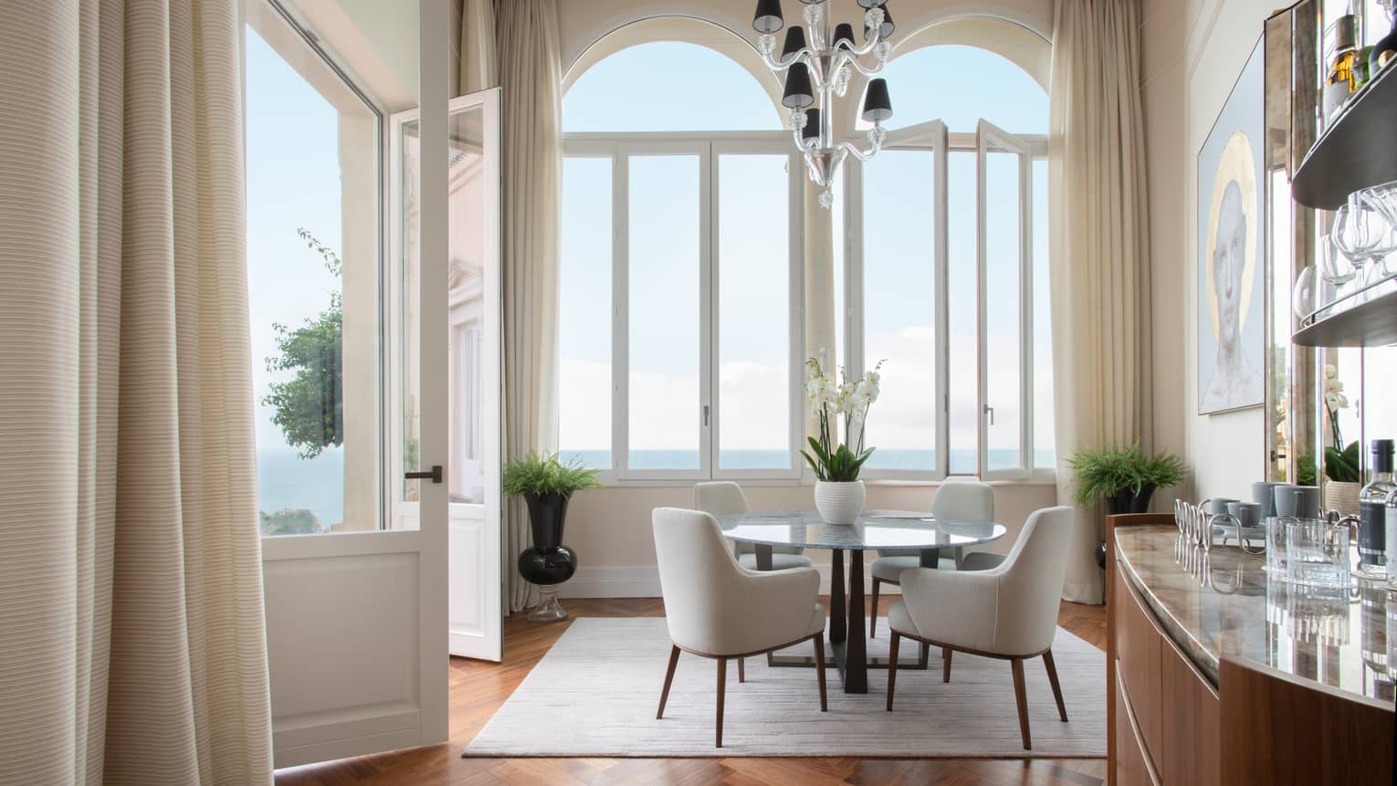 Elegant dining room, table with four chairs, tall windows with sea view