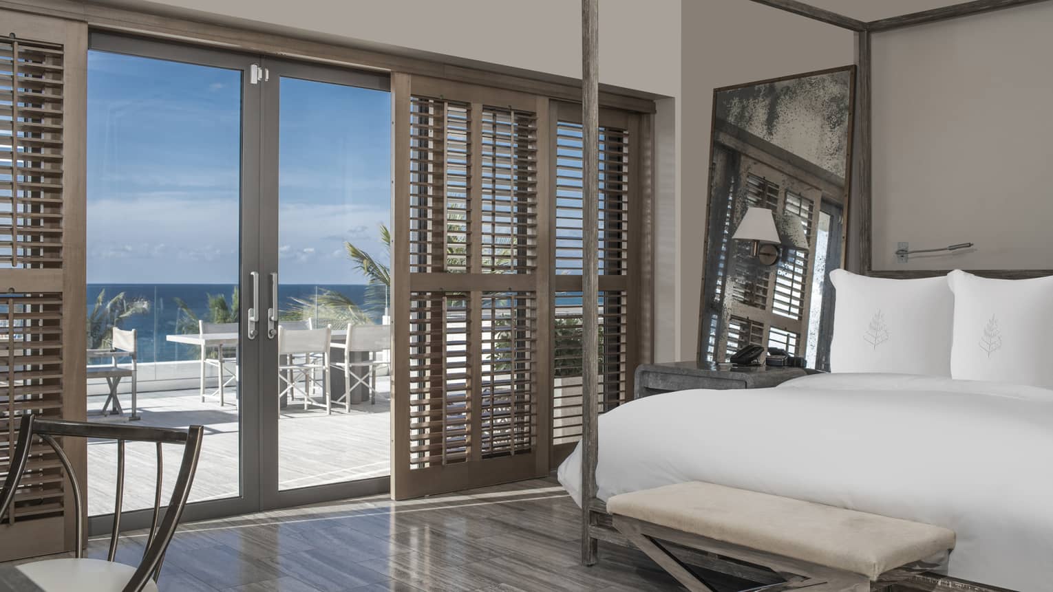 Bedroom with four-post bed, shutter sliding doors opening to sea-view terrace