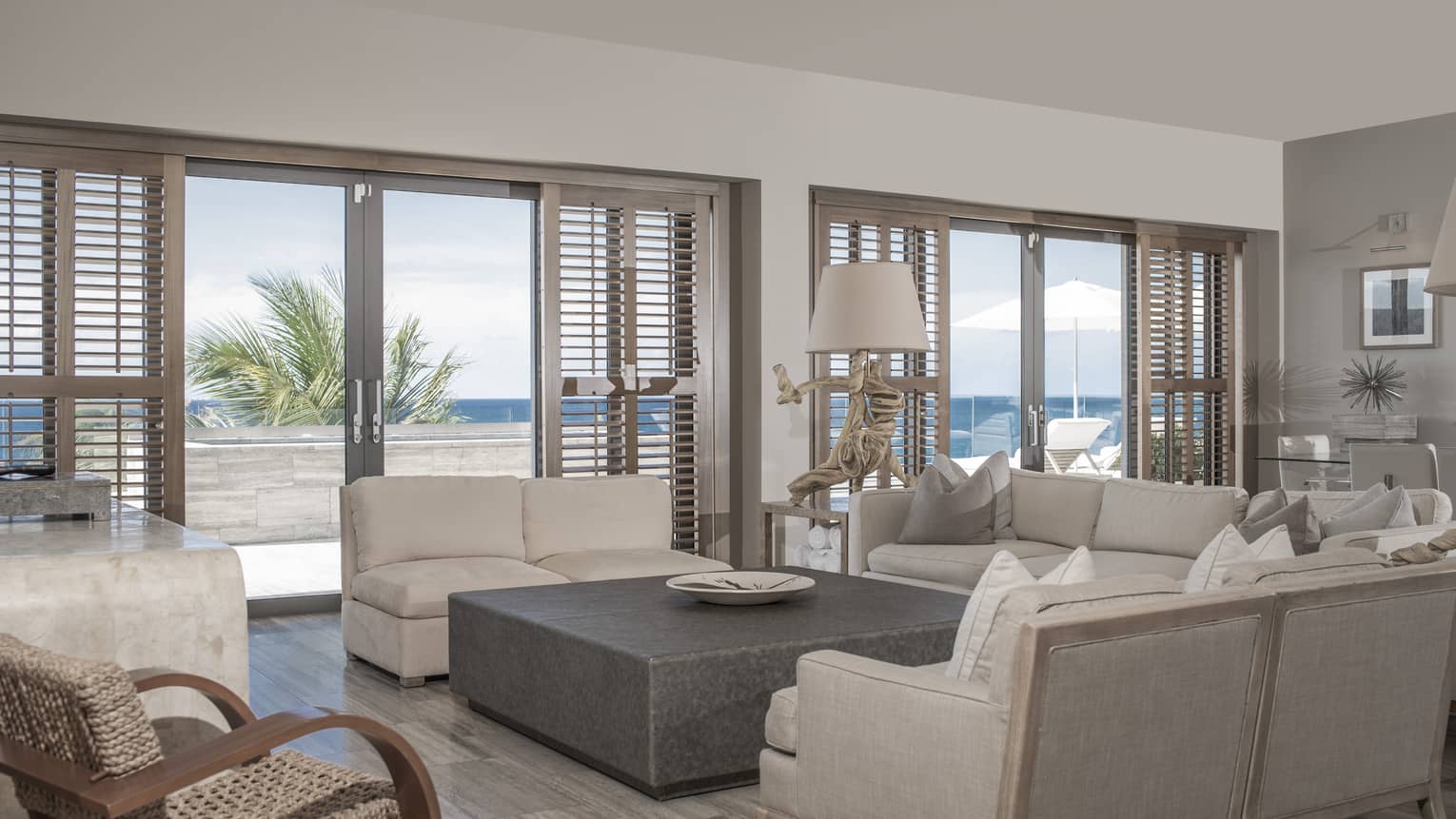 Living room with large sectional, light grey sofa, large square coffee table, sea view
