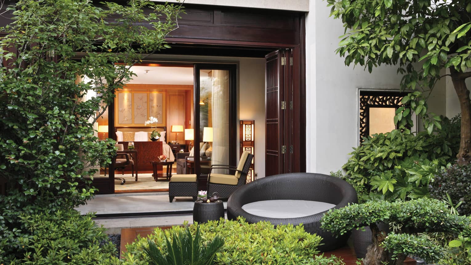 Grand Premier Room patio garden, large round black wicker chair, open villa door