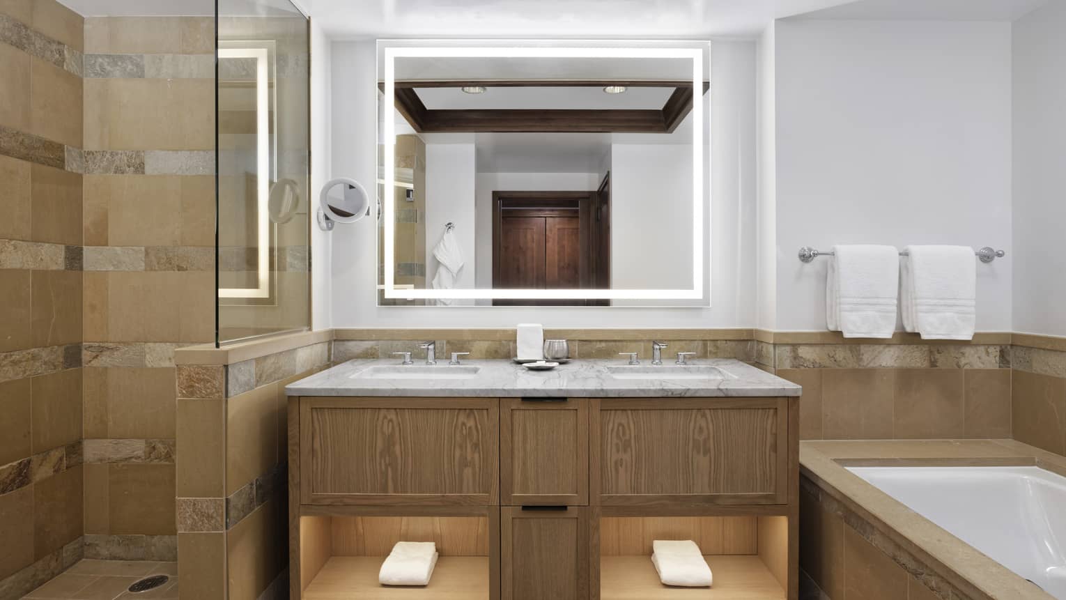 Bathroom with tub and separate glass shower, illuminated mirror and double vanity
