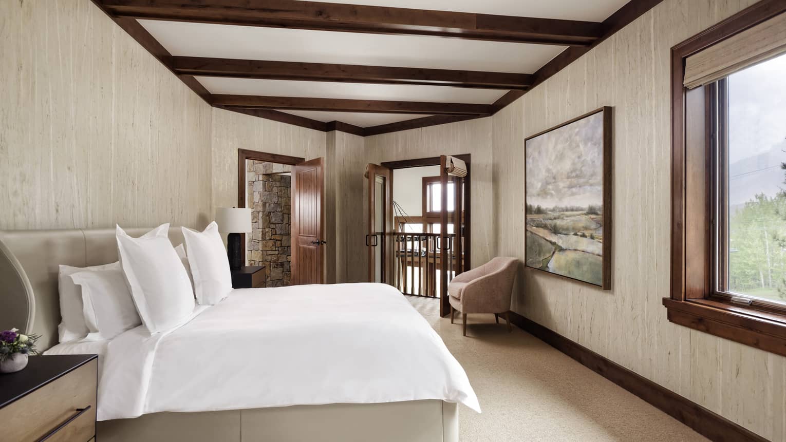 Bedroom with king bed, wooden beam ceiling, artwork and window