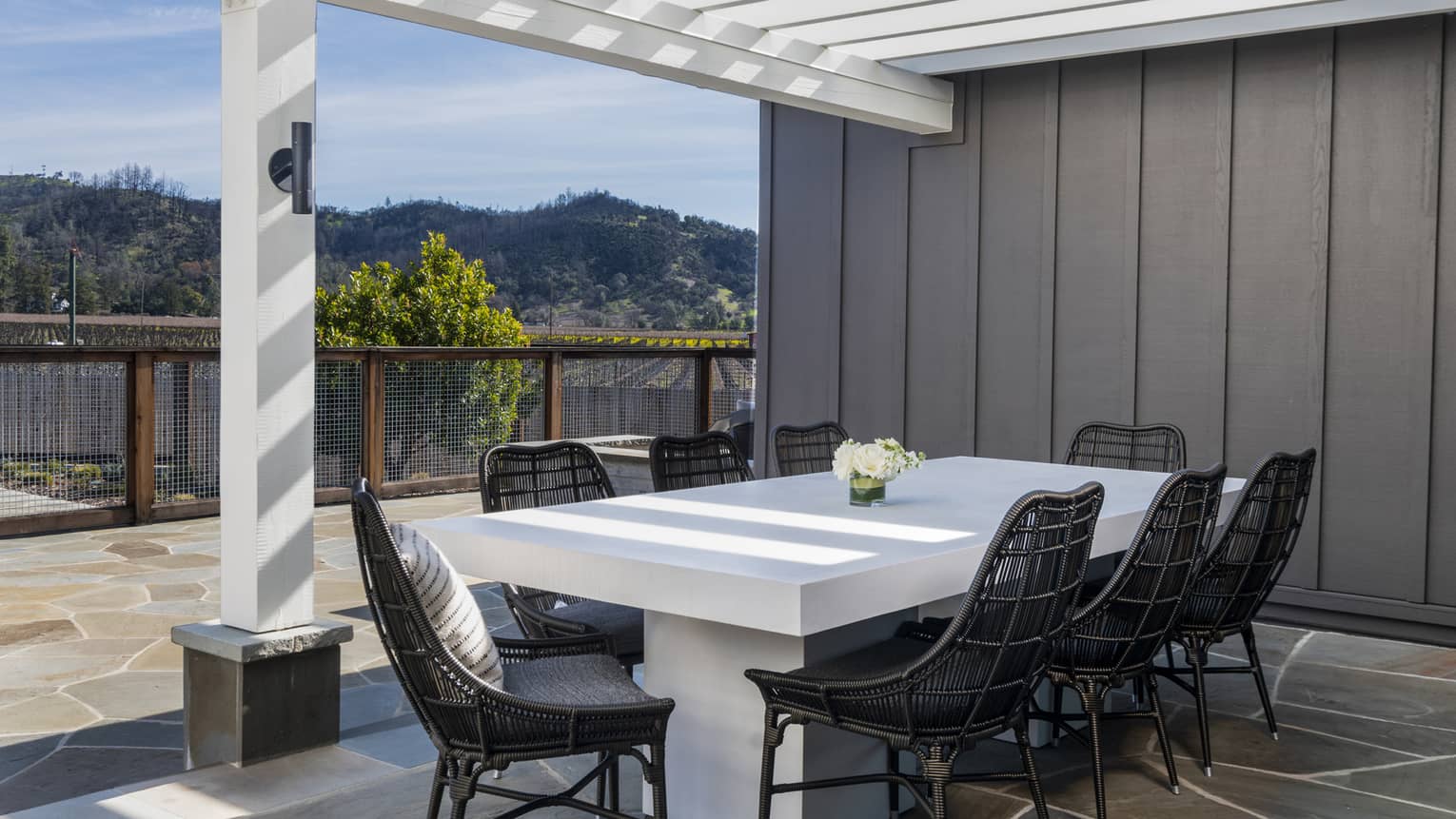 Dining table for 8 on stone patio under a white pergola