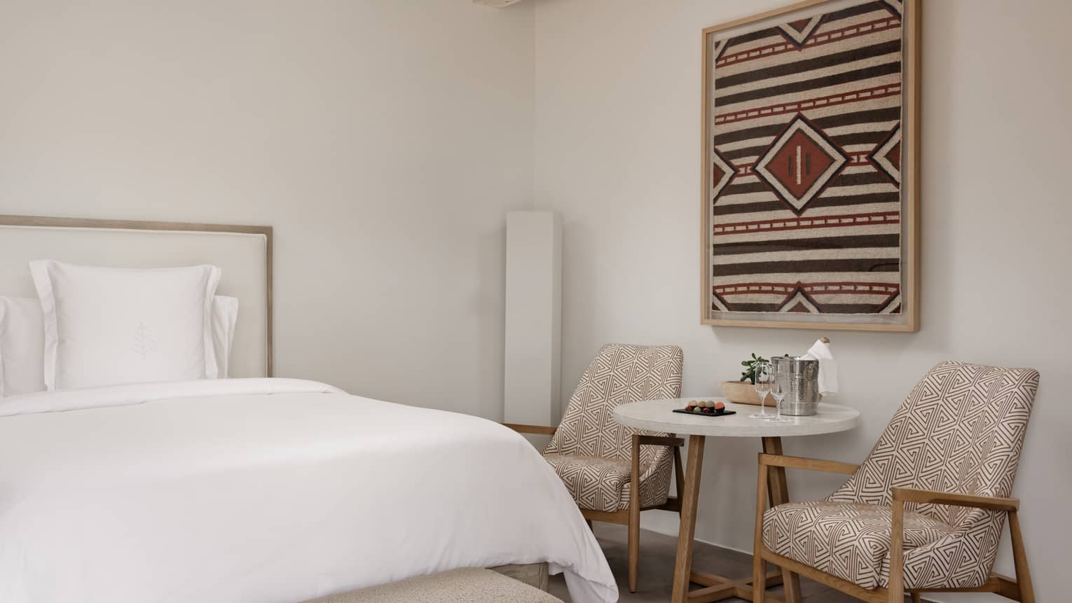 Queen bed, small table and two chairs in deluxe room at Four Seasons Resort Santa Fe