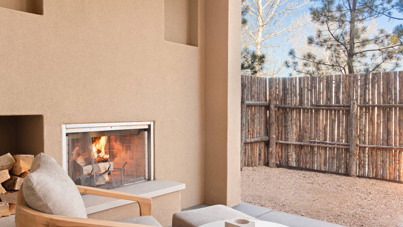 Fireplace and lounge chair on a private patio of Casita Room at Four Seasons Resort Santa Fe