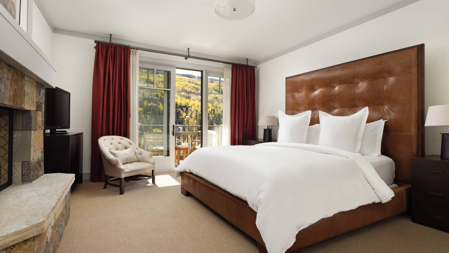 A private vail residence bedroom has a king size bed with a tall leather headboard 