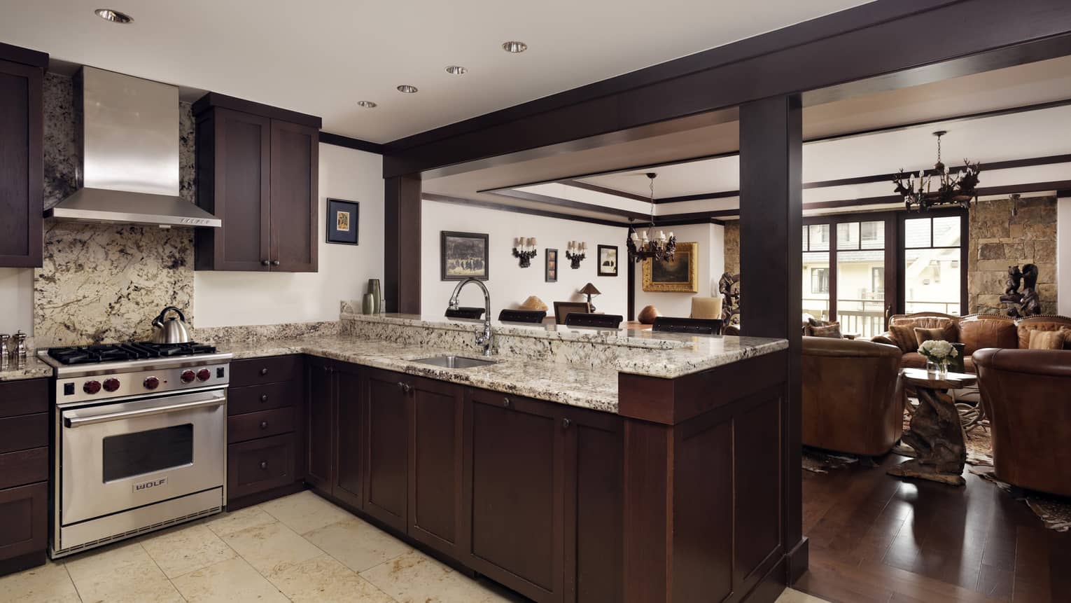 Kitchen with dark wooden cupboards, granite counters, gas range