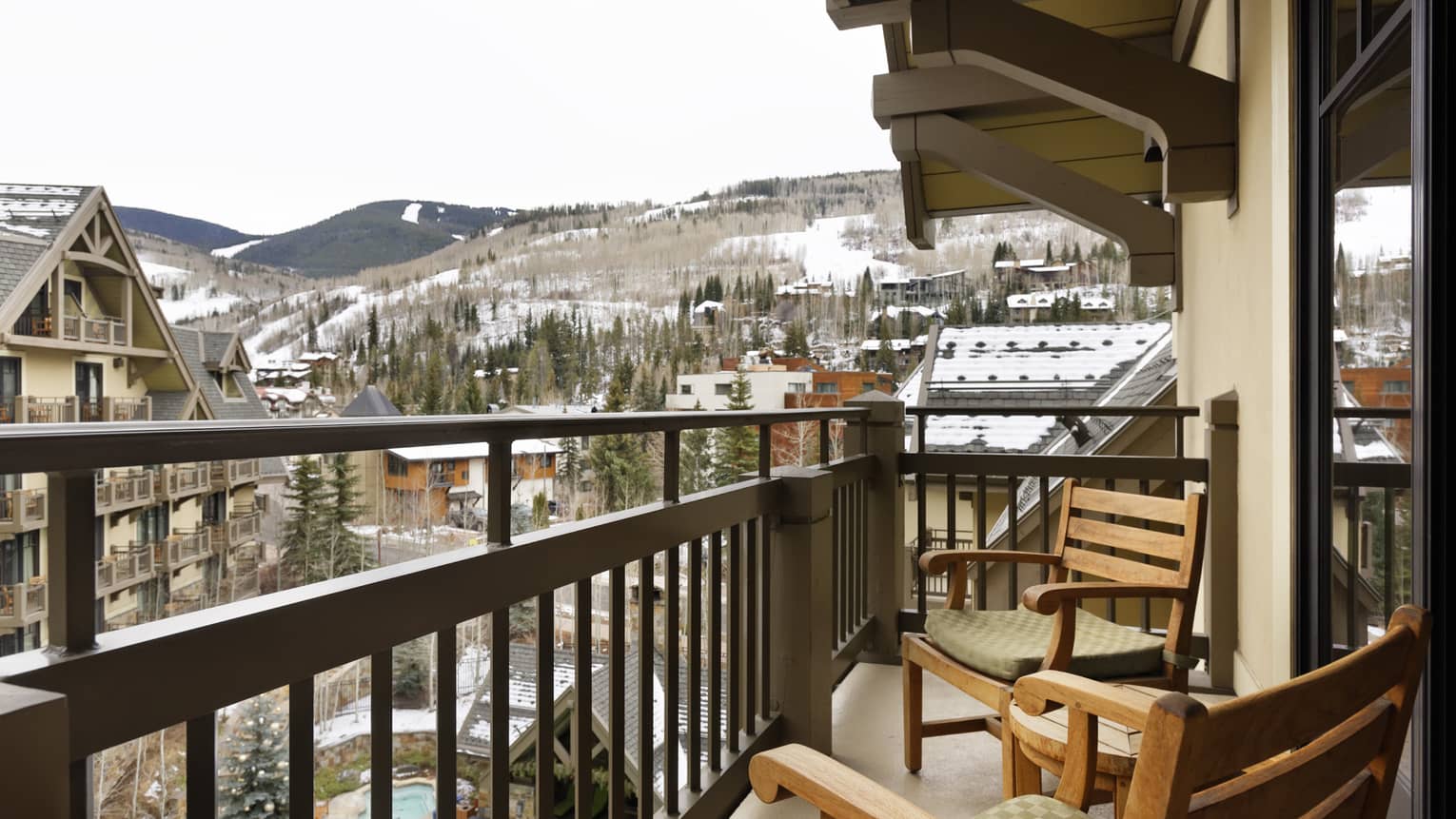 Outdoor balcony with two wooden chairs, overlooking Four Seasons Vail and mountains