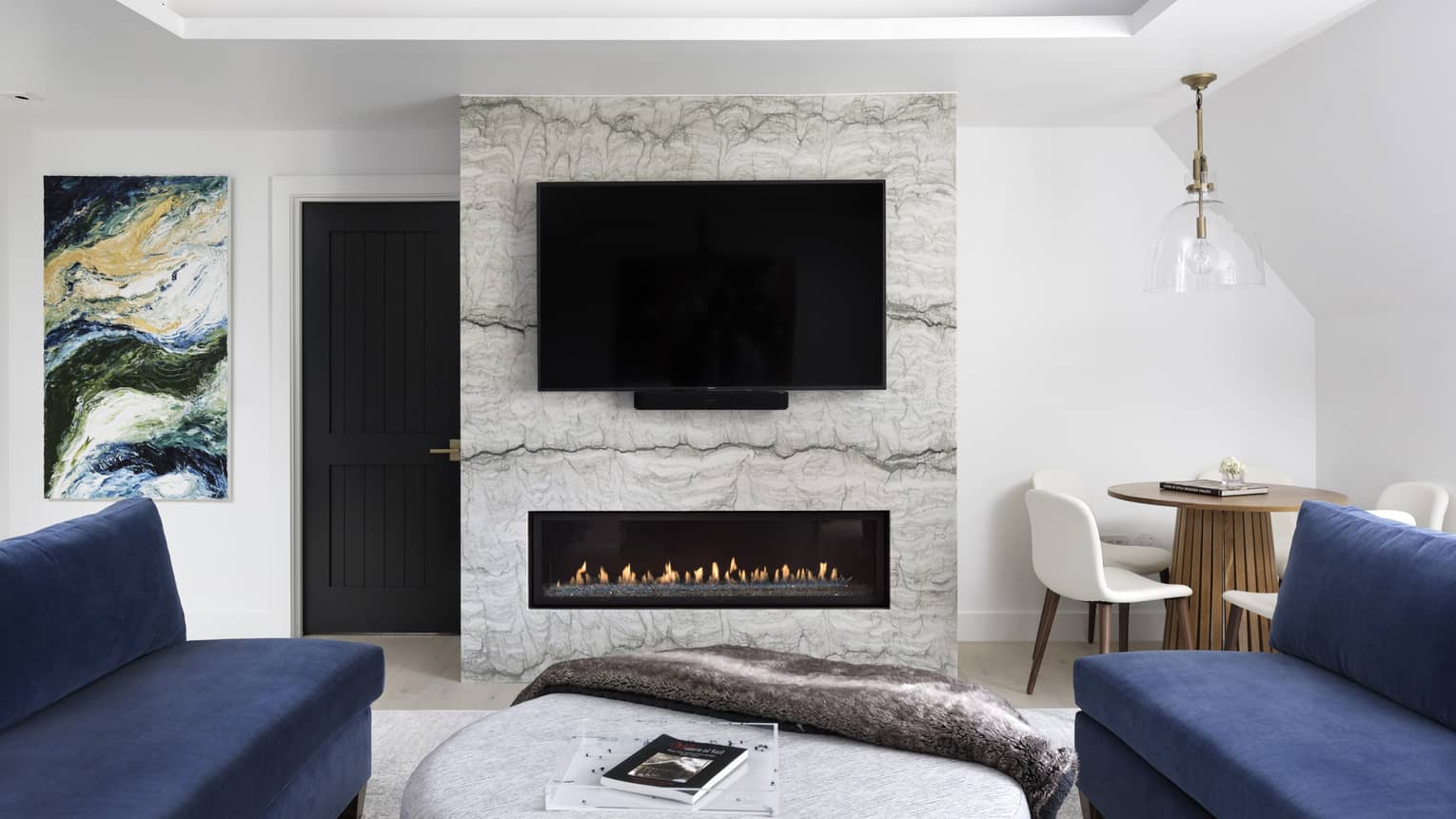 Modern fireplace with marble hearth, flat-screen TV, two dark blue sofas
