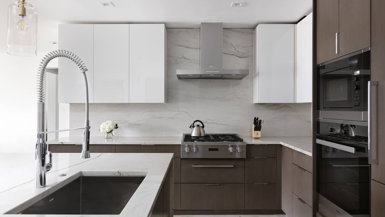 Kitchen with white cupboards and white marble countertops, dark wood lower cabinets