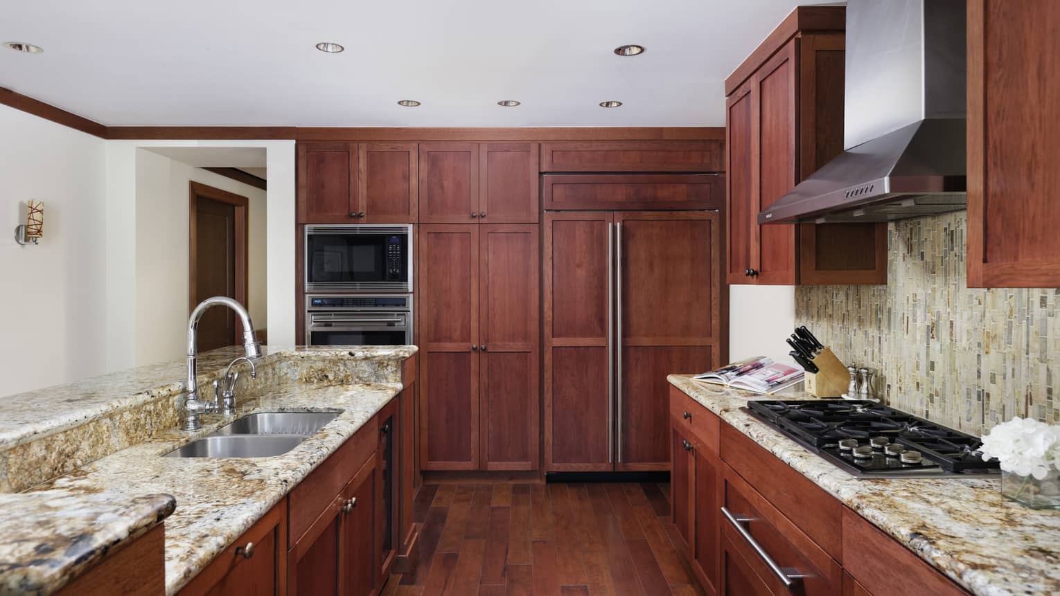 Kitchen with rich wood cabinets, natural-colored granite counters