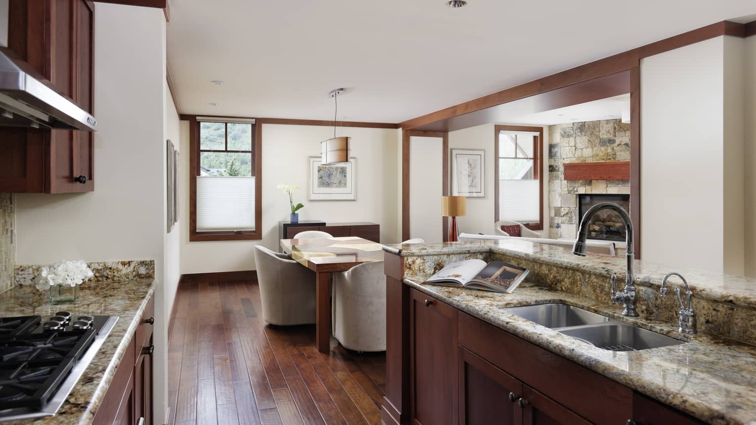 Kitchen opening to dining room, rich wooden floors, granite countertops