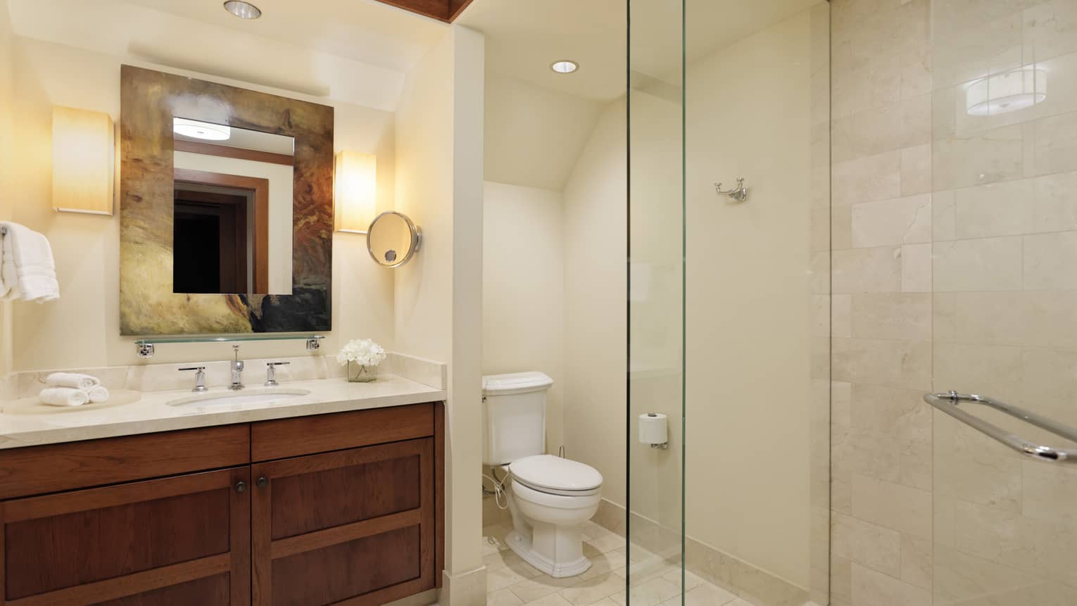 Bathroom with glass-enclosed shower, wooden vanity, toilet