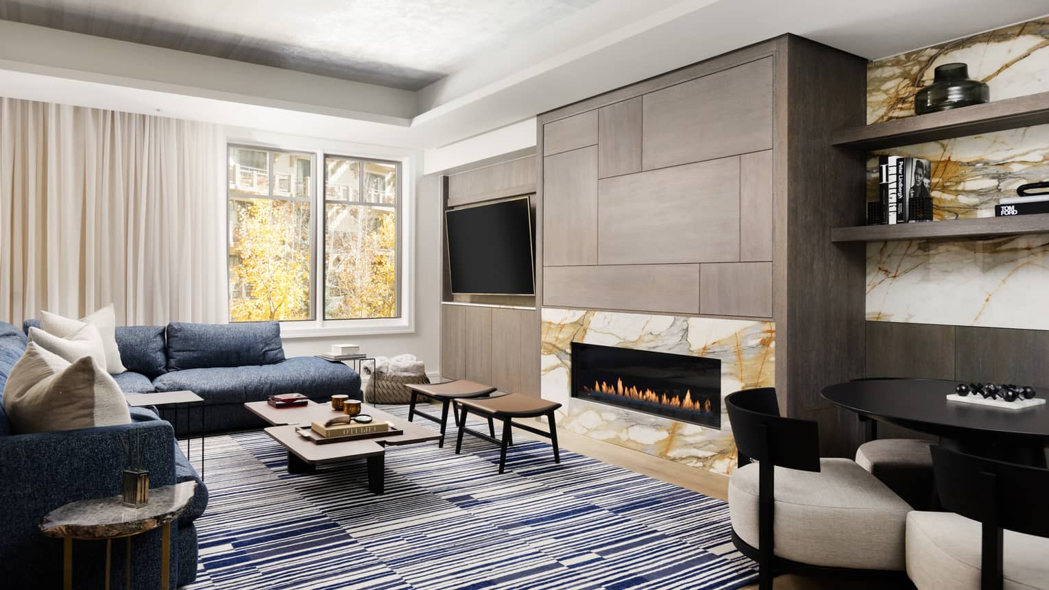 Light-filled living room with modern rectangular fireplace, blue sectional, blue and white rug