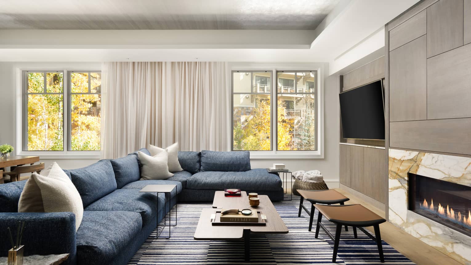 Living room with large blue sectional sofa, modern wooden coffee table, windows