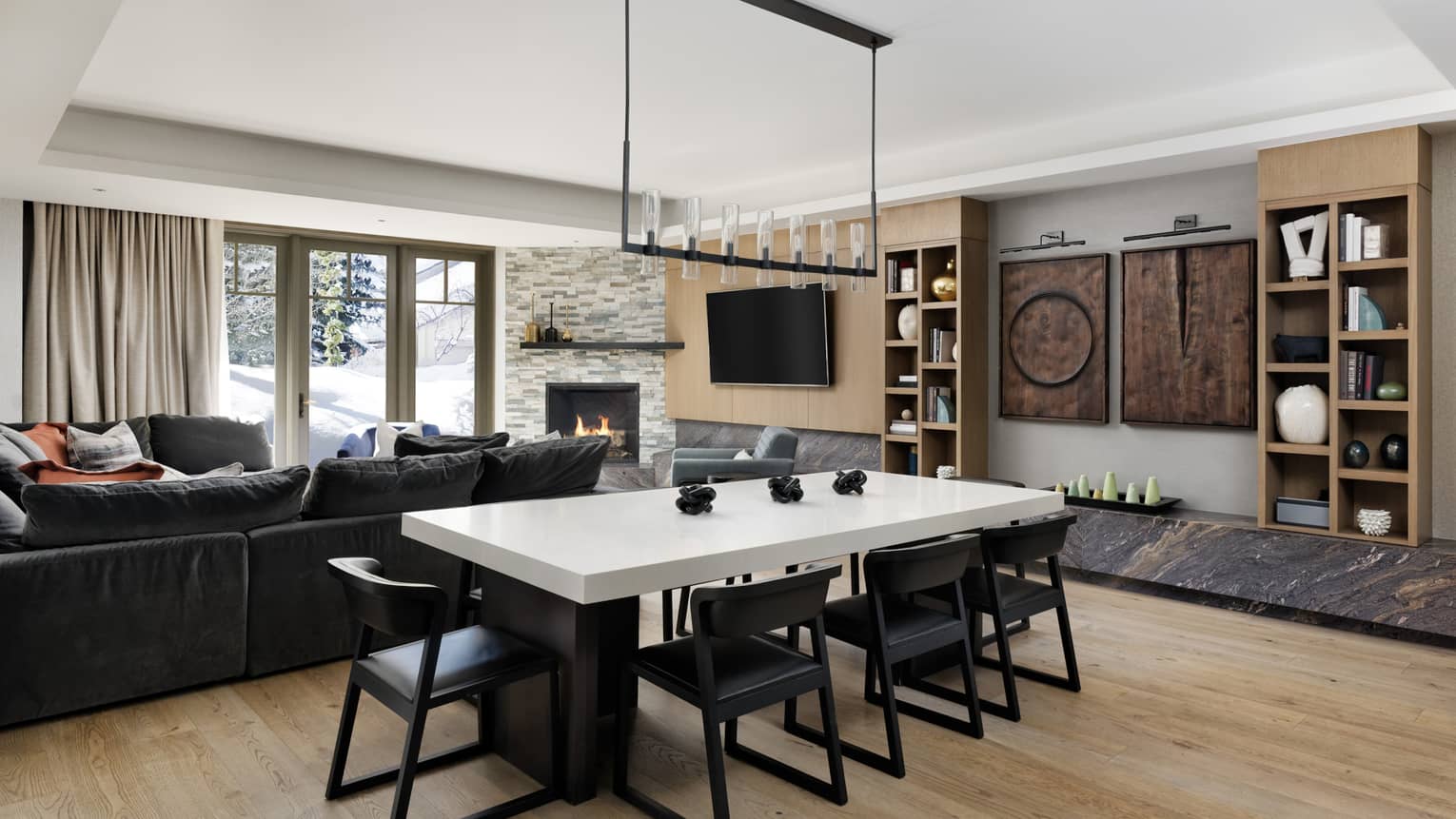 Dining room with white-topped table, 8 black chairs, modern lantern-like light