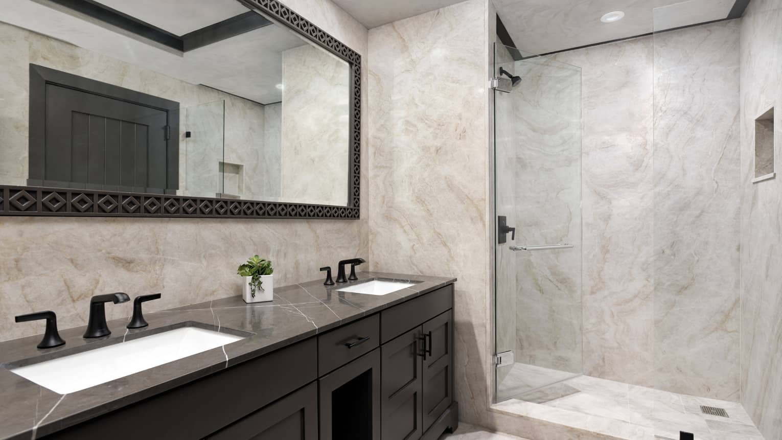 Bathroom with granite walls, glass walk-in shower, double vanity with dark cabinets