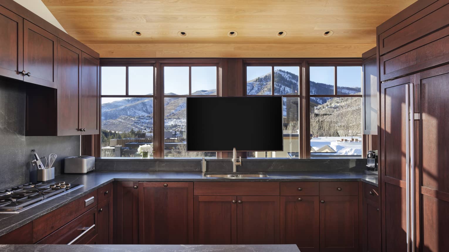 Kitchen with walnut cabinets, windows and TV
