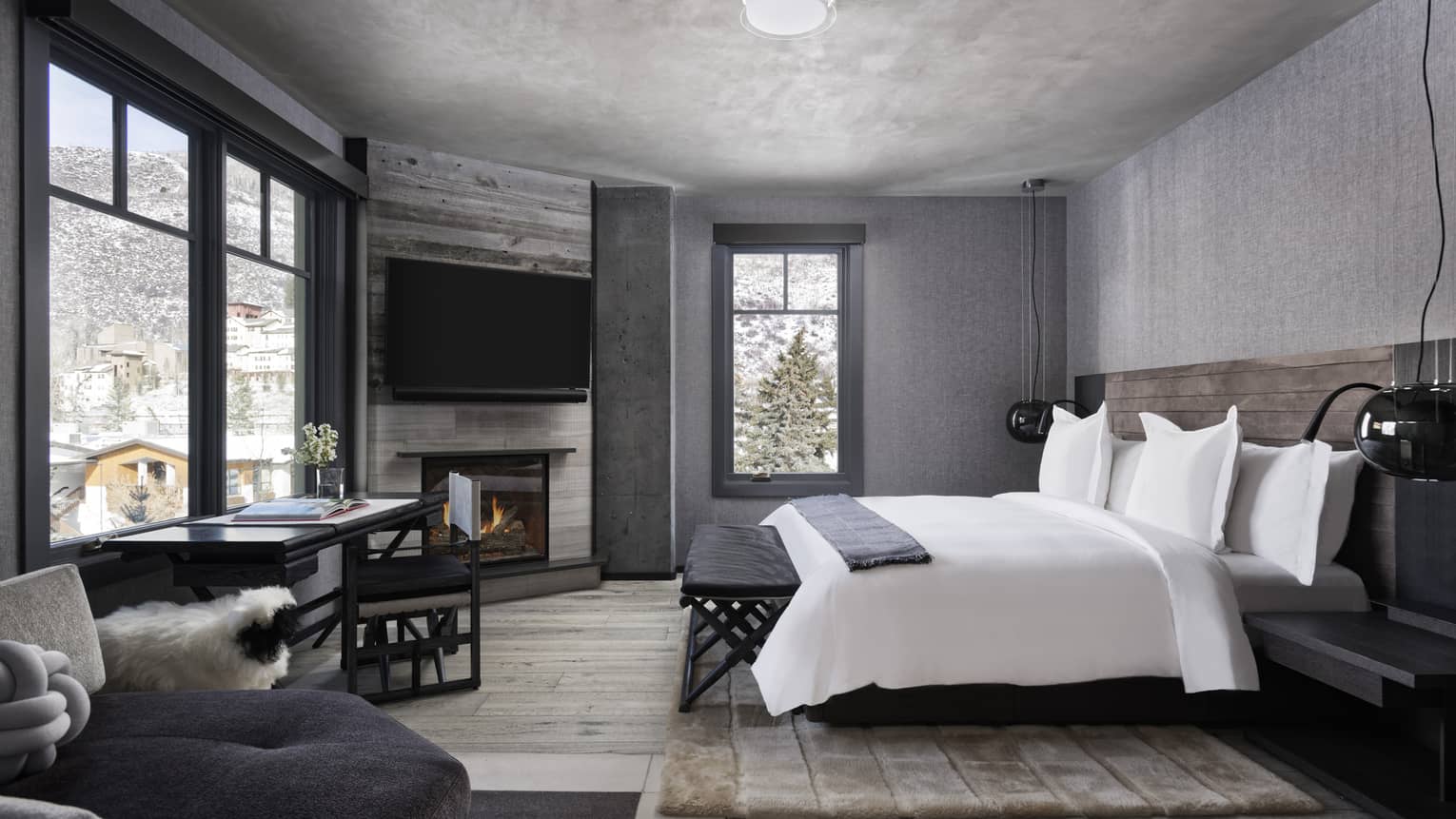Mountain chic bedroom with white king bed, wall-mounted TV above fireplace