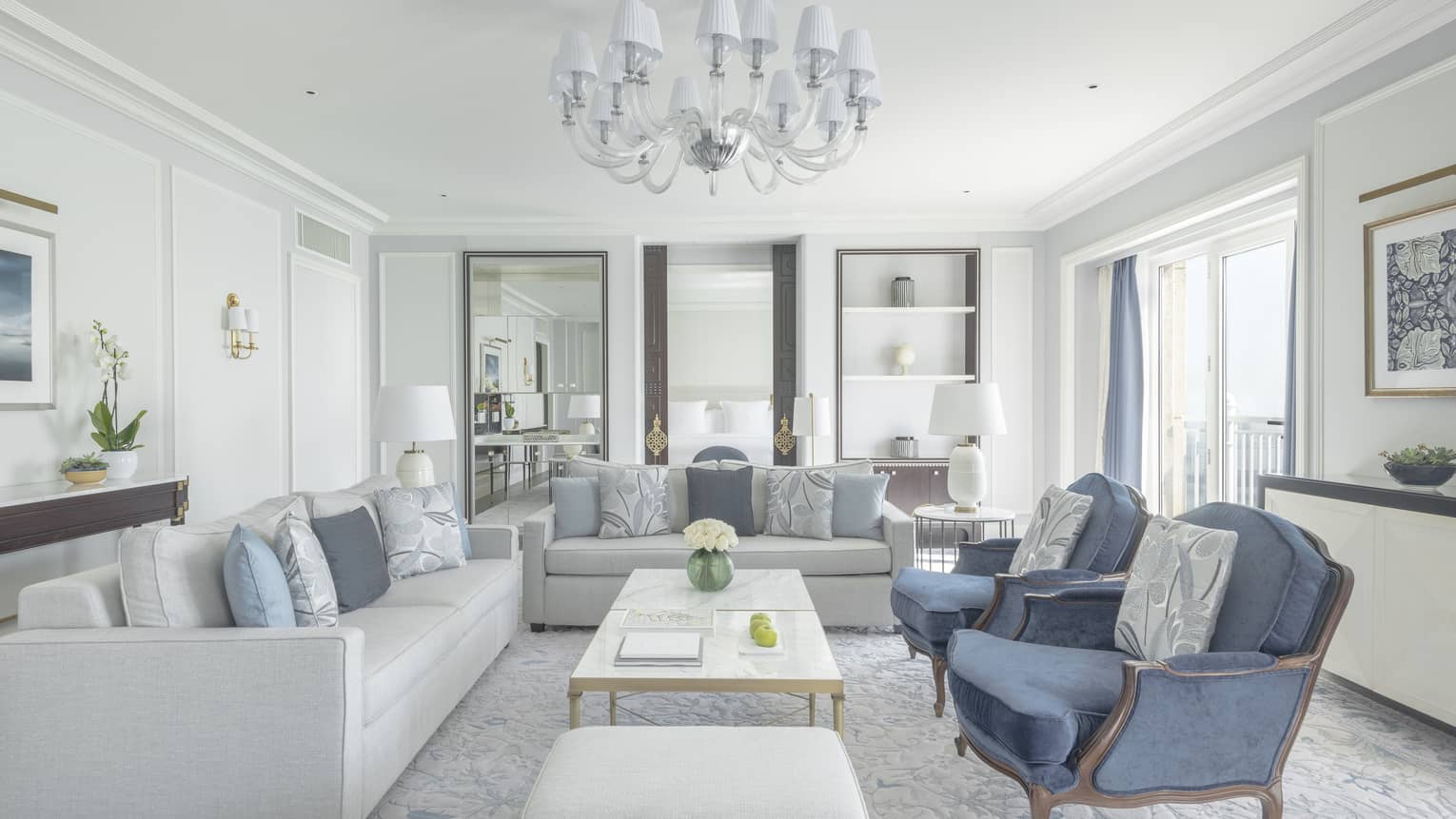 Elegant living room with two light great sofas, two blue arm chairs and white chandelier