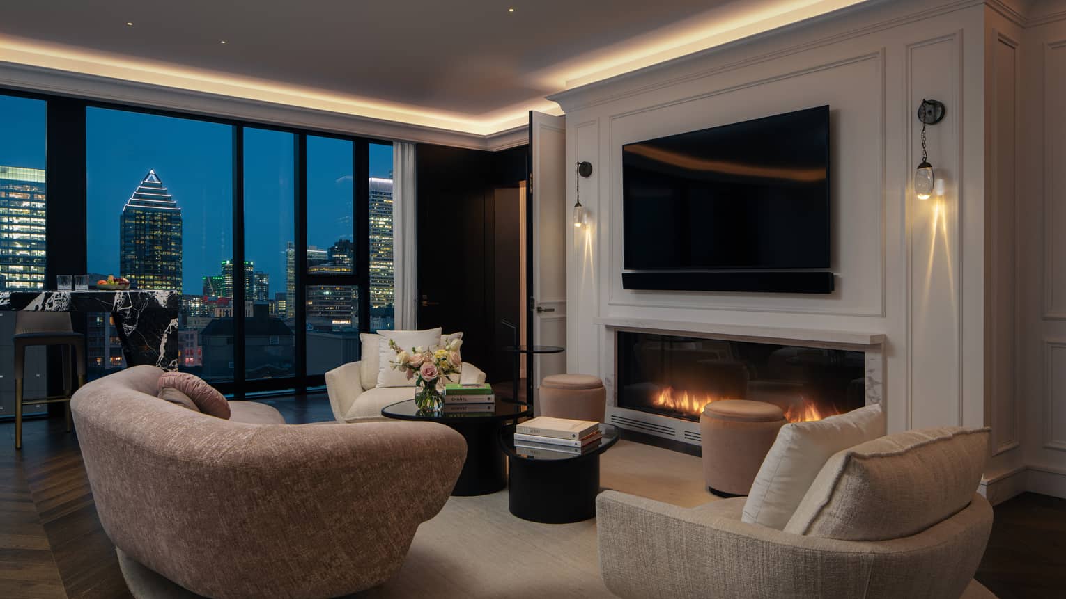 Living room with modern curved sofa and chairs, fireplace, TV and city evening view