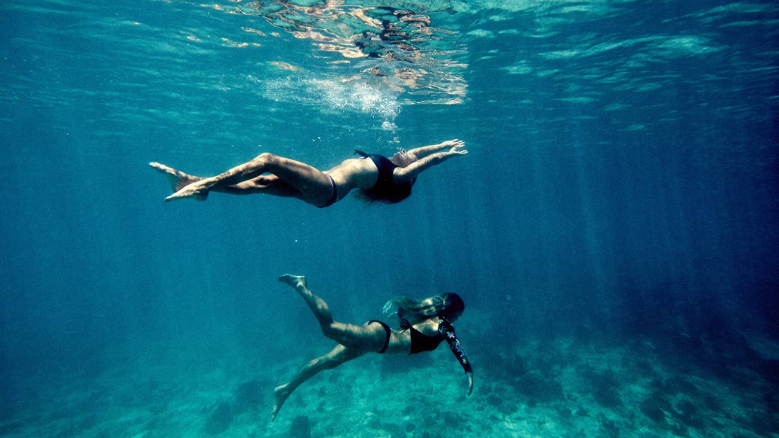 Underwater view of two women swimming in ocean