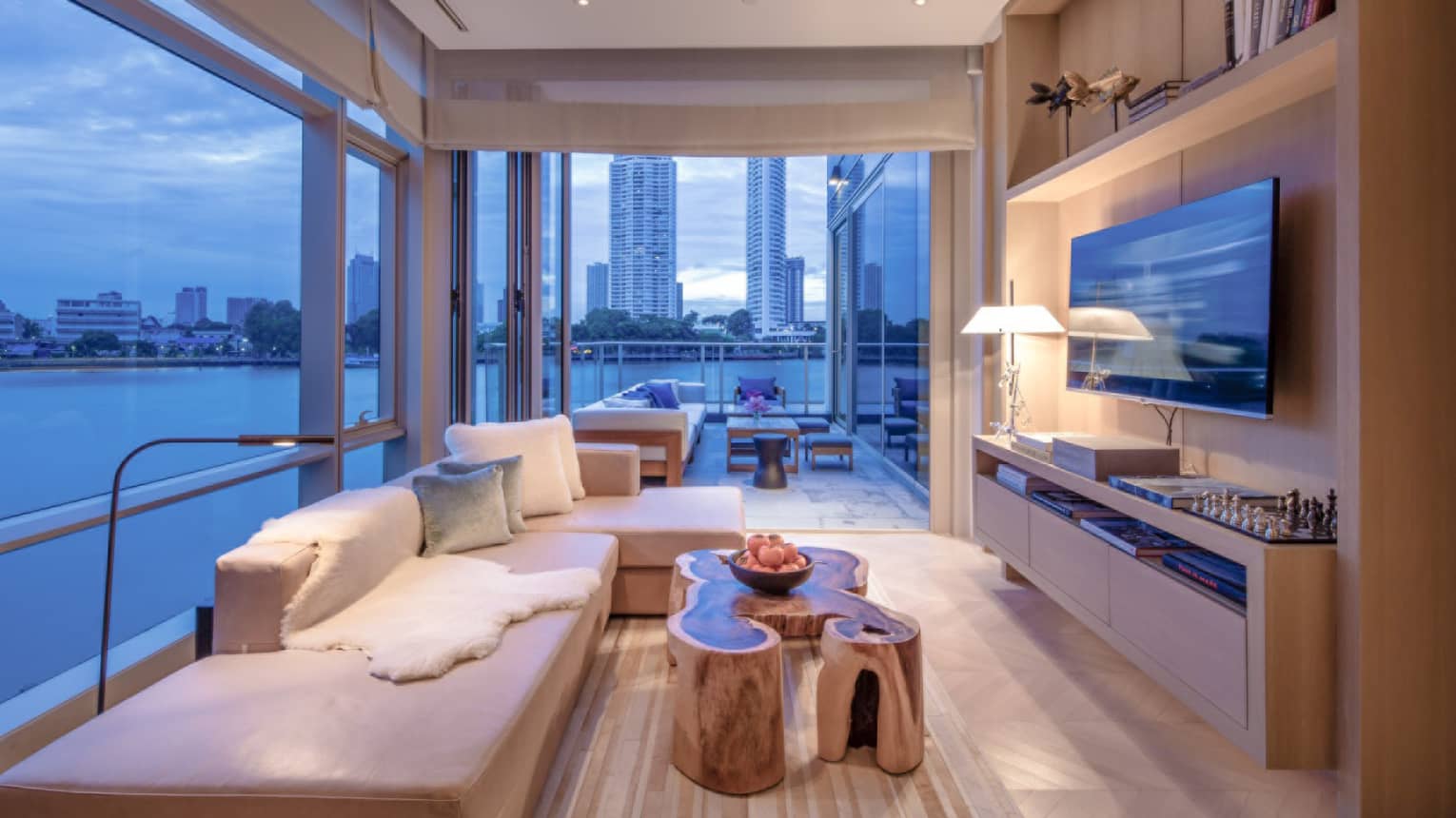 Living room with couch, coffee table and floor-to-ceiling windows with water and city view.