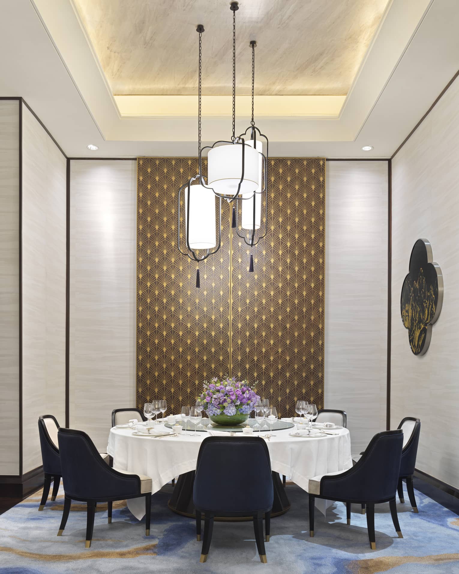 Zi Yat Heen private dining room with round table and white linens, eight blue chairs, watercolour carpeting, triple light fixtures from ceiling